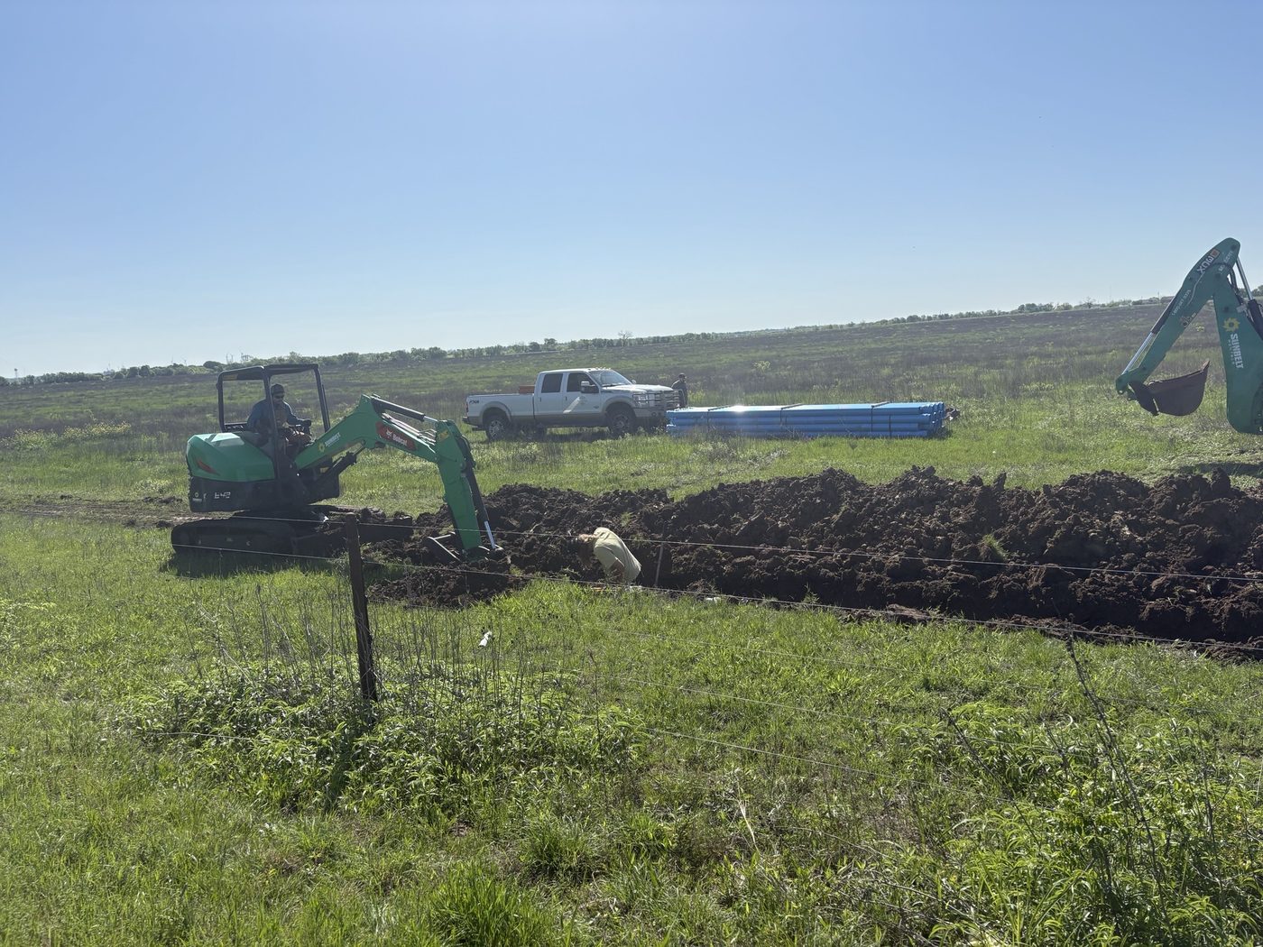 Excavator working the waterline trench on the property